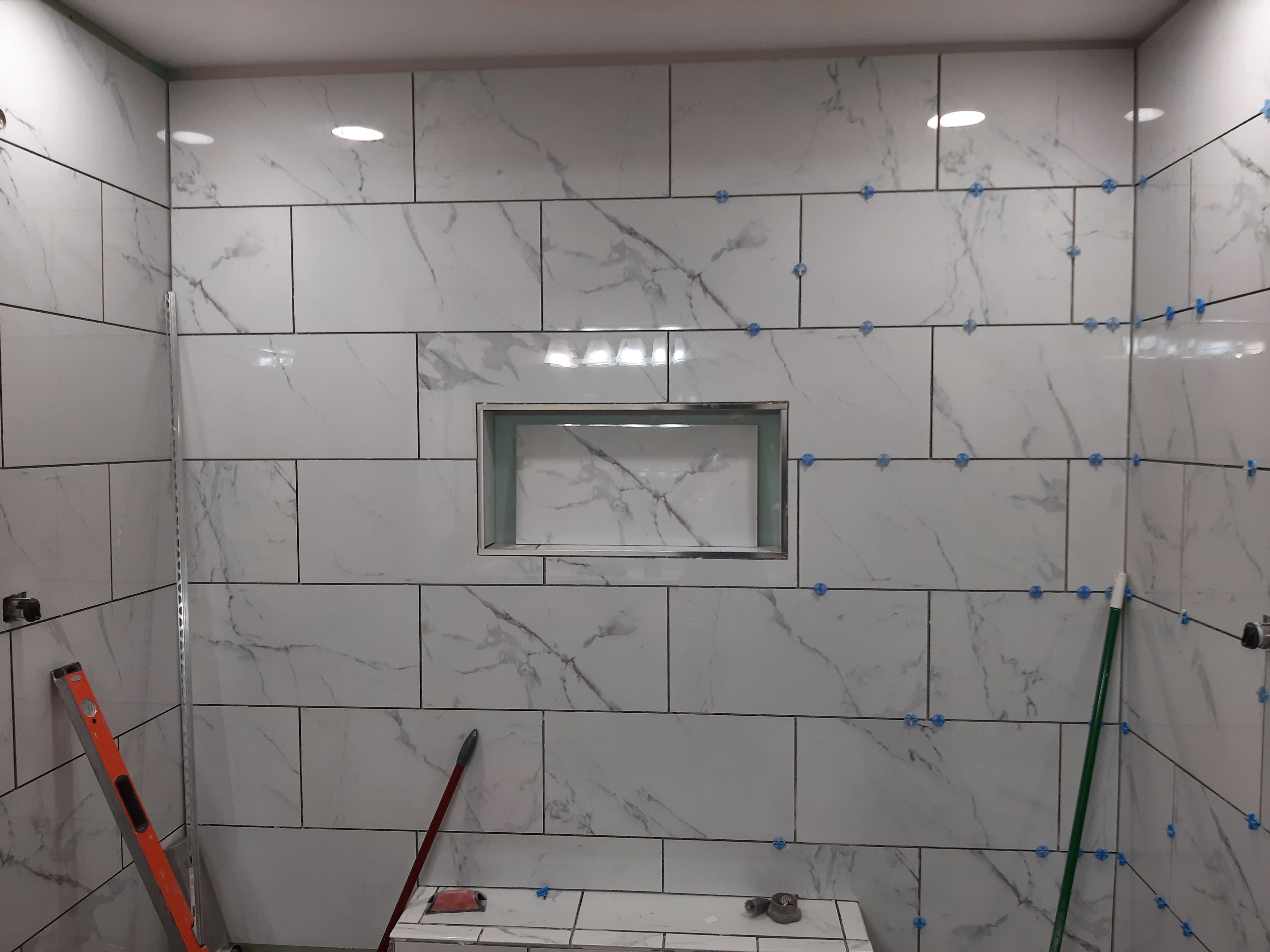 Marble tile shower wall installation in progress