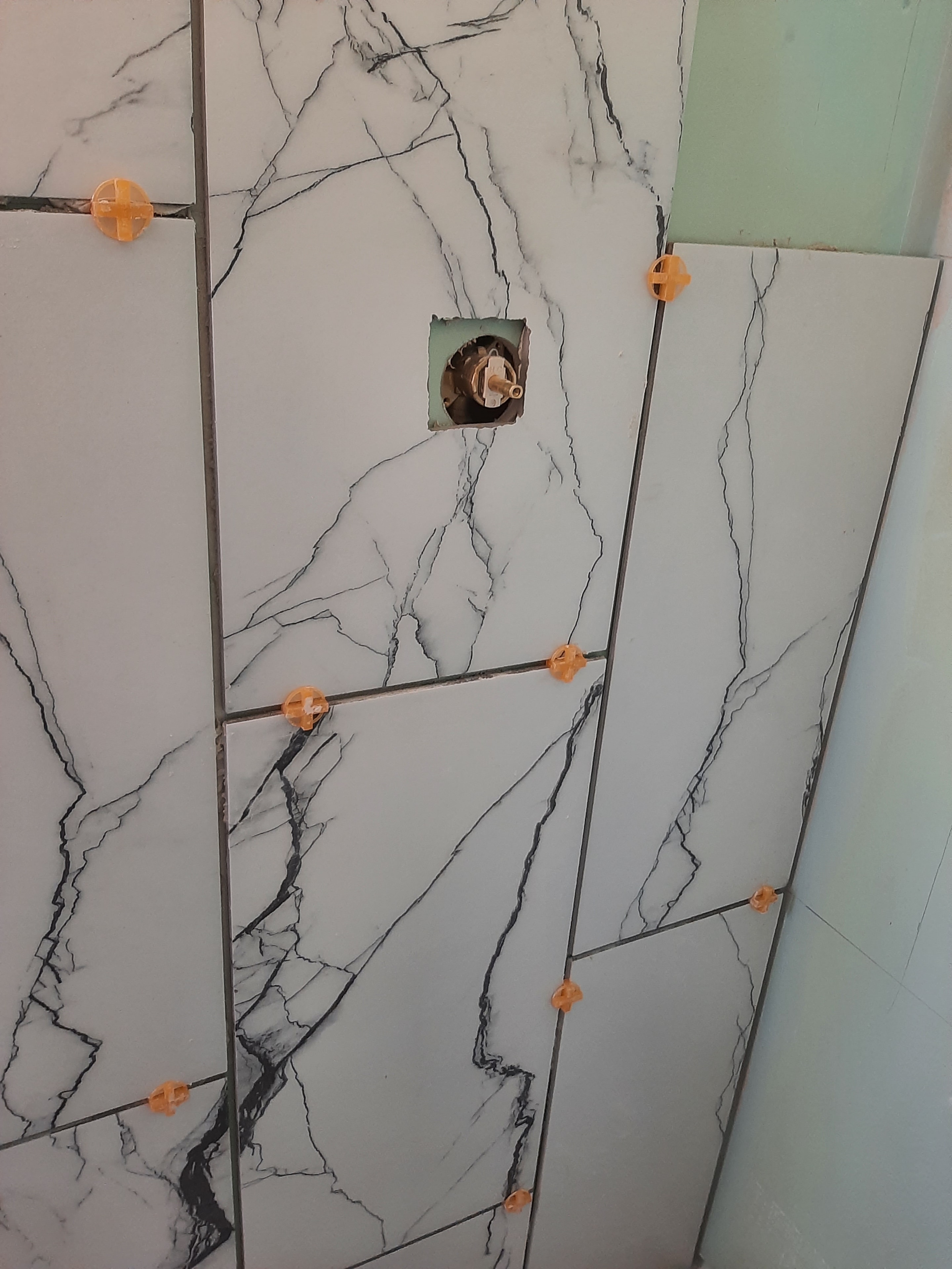 Large-format marble tile going up on shower wall