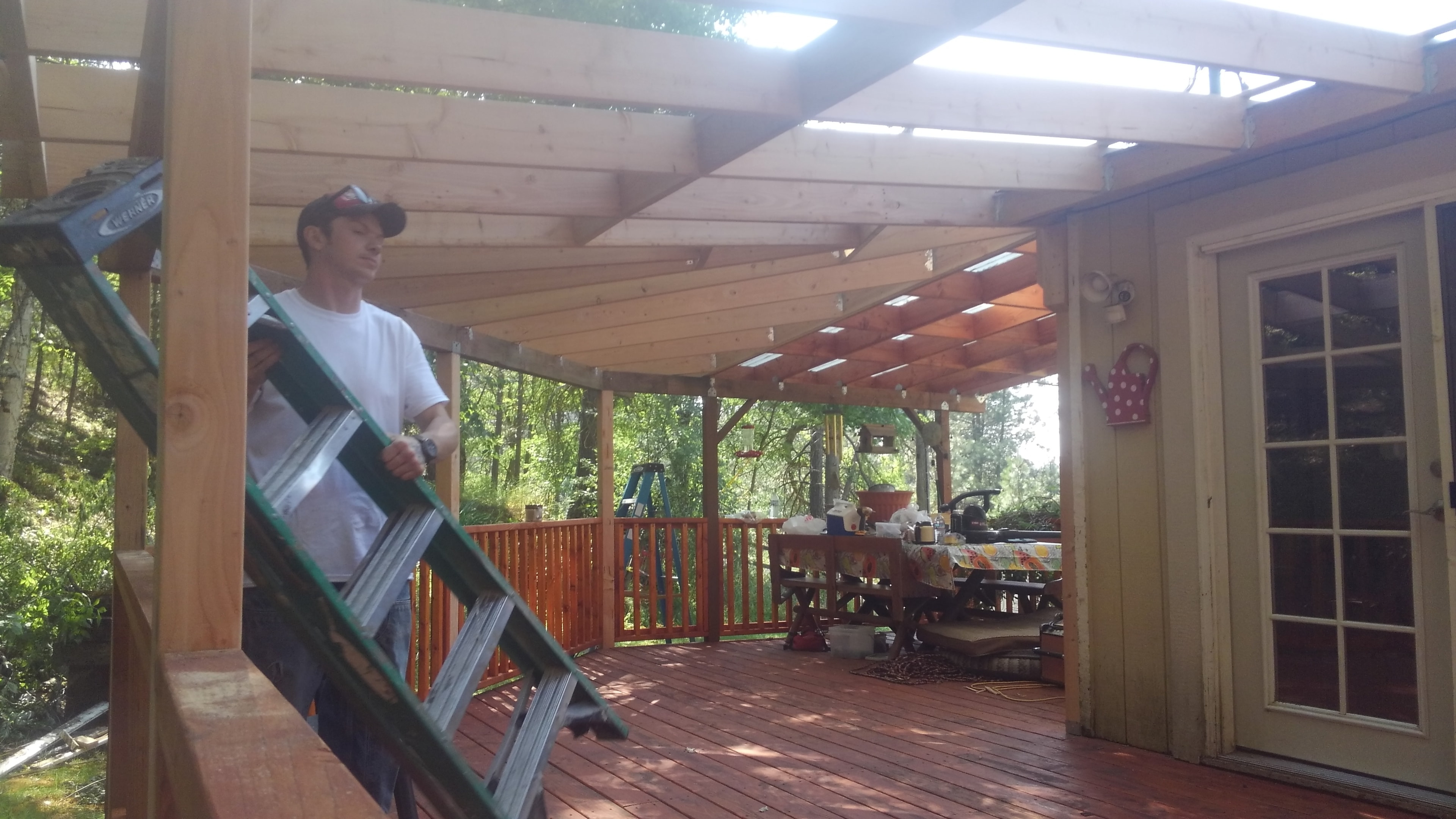 Worker installing covered pergola over stained deck